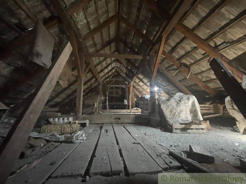 Attic storage space of a family house with wooden beams and a layer of dust.