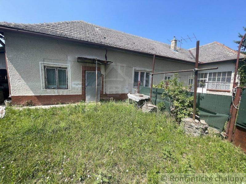 The back part of a family house in Nové Zámky with a grassy yard and older equipment.