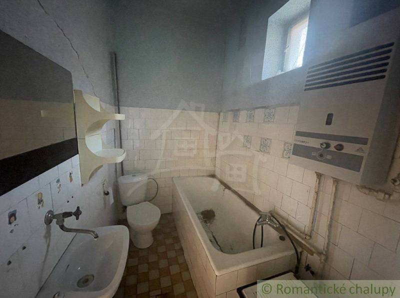 A bathroom in a family house with a bathtub, sink, toilet, and water heater.
