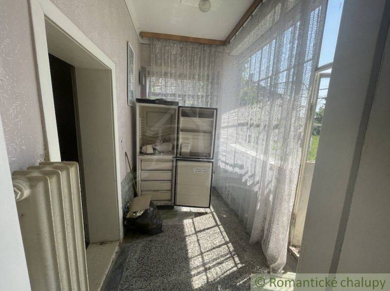 Hallway with a refrigerator, curtains, and a radiator in a family house.