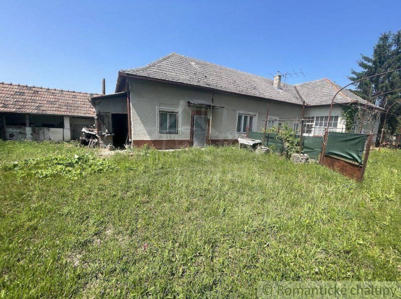 A family house in Nové Zámky with a large grassy garden and an adjacent building.