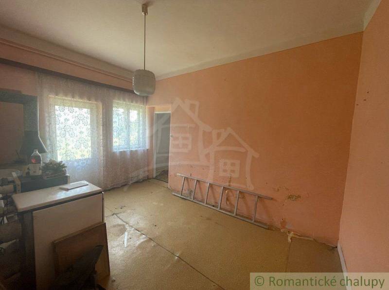 A room in a family house with orange walls, curtains, and white furniture.