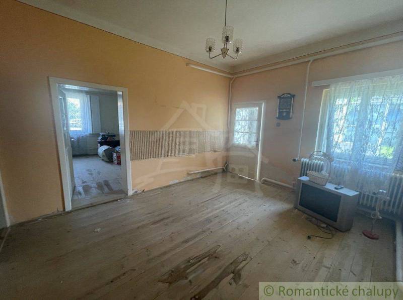 A spacious living room in a family house with wooden flooring and an older television.