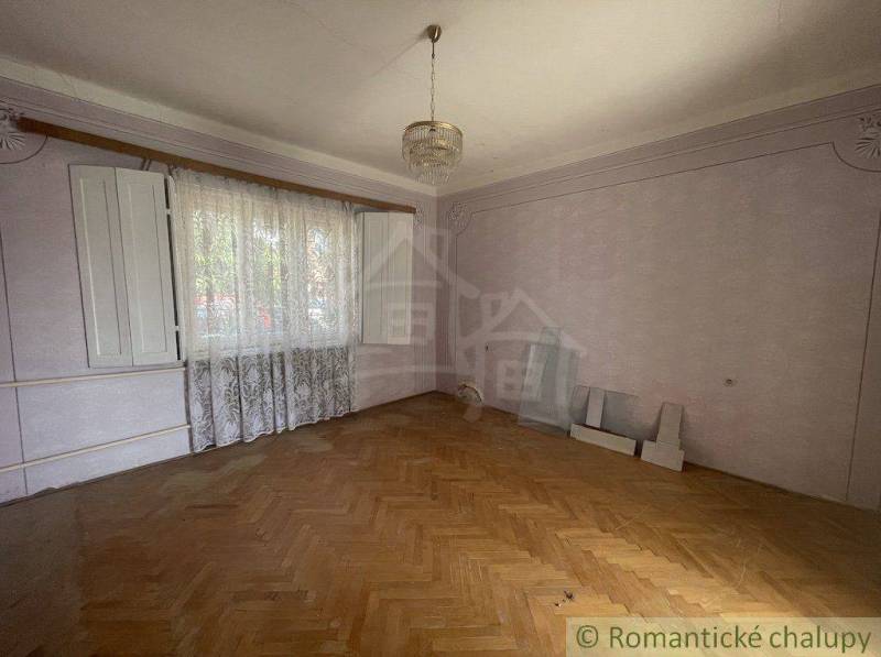 An empty room with a wooden floor and an open window in a family house.