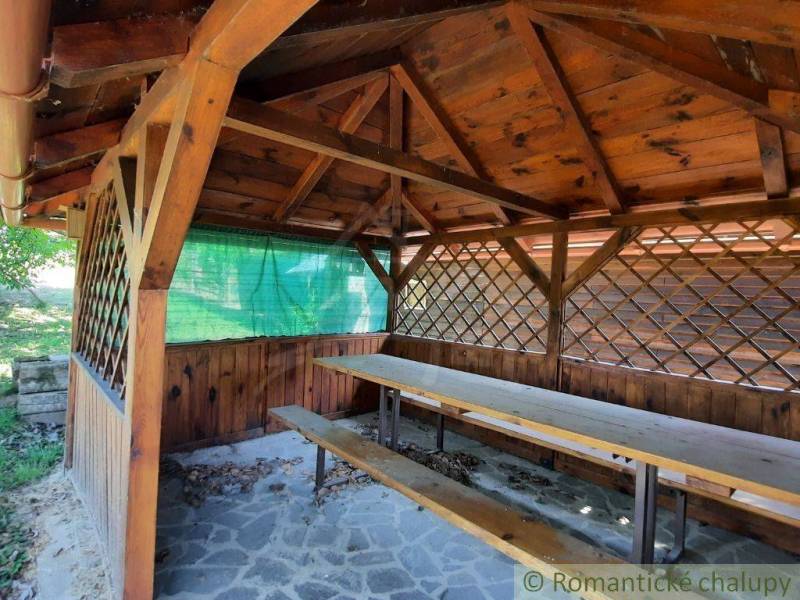 A wooden pergola at the cottage in Malé Kozmálovce with a long bench and a table.