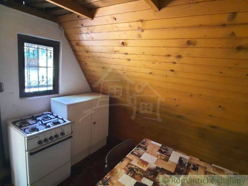 Rustic kitchen in a cottage with a gas stove and wooden paneling.