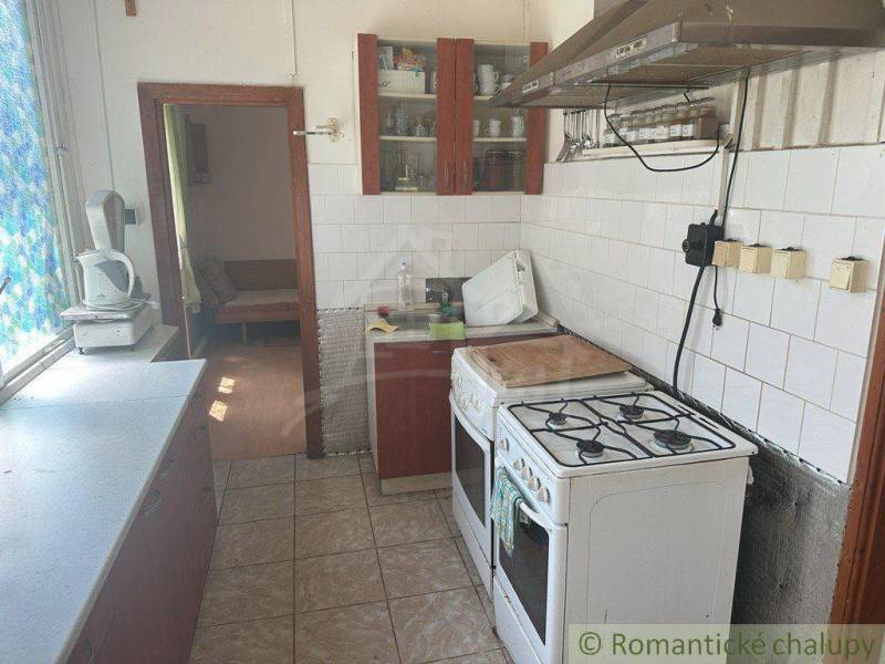 A family house kitchen with a gas stove and a window with blinds.