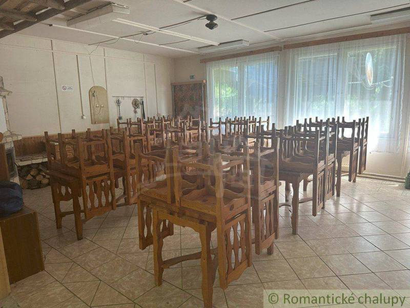 A dining room with wooden chairs on the tables in a family house.
