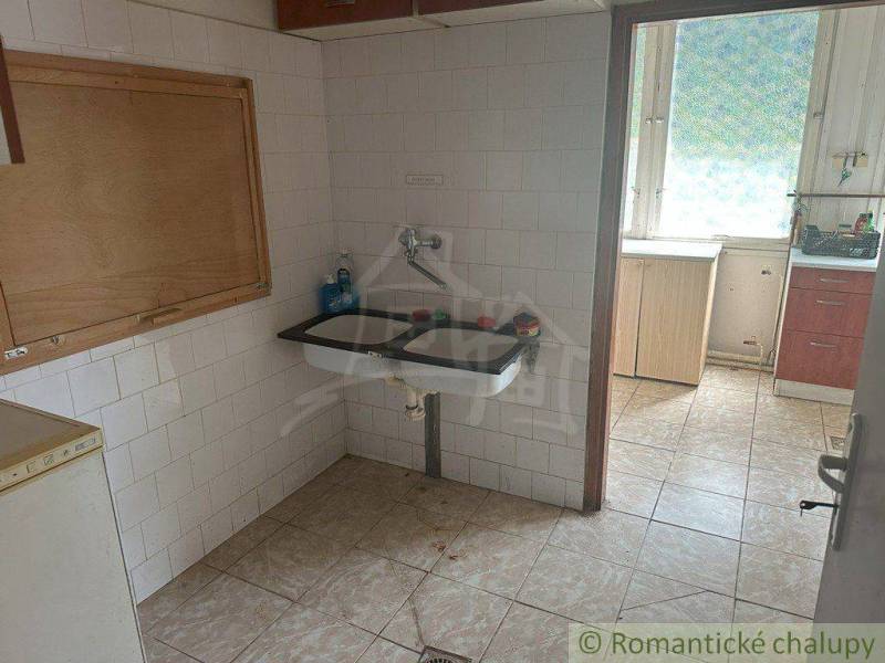 A kitchen in a family house with a tiled floor and a classic ceramic sink.