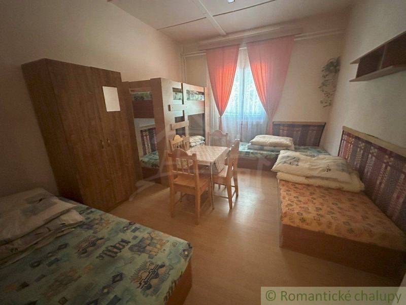 A room with a bunk bed, separate beds, a table, and a wardrobe in a family house.