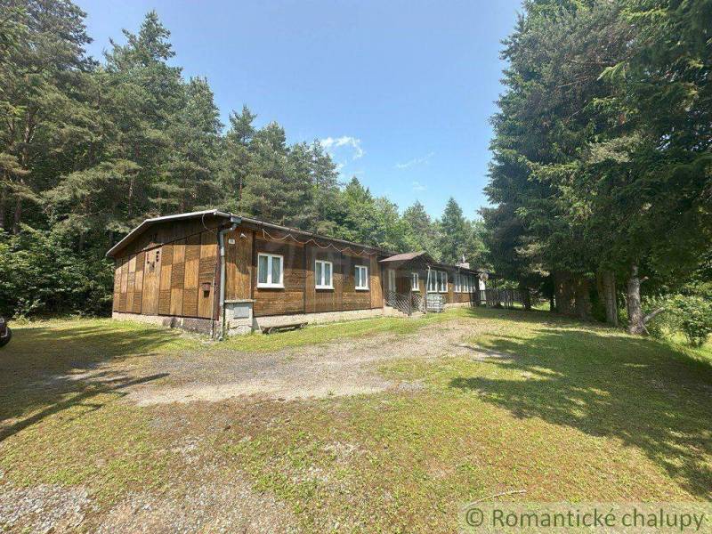 A family house in Poltár with a garden surrounded by forest and coniferous trees.