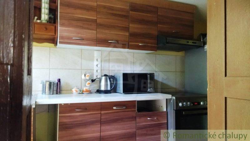 A kitchen in a cottage with a wooden kitchen unit, an electric kettle, and a microwave.