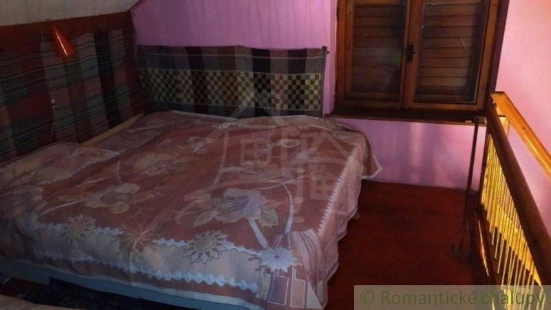 A bedroom in a cottage with a wooden bed and pink walls, feels cozy.