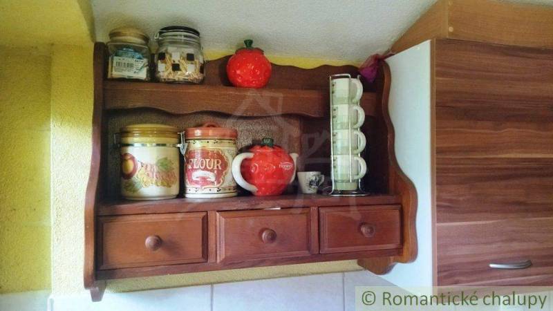 Wooden shelf with jars and cups in the cottage. Cheerful kitchen atmosphere.
