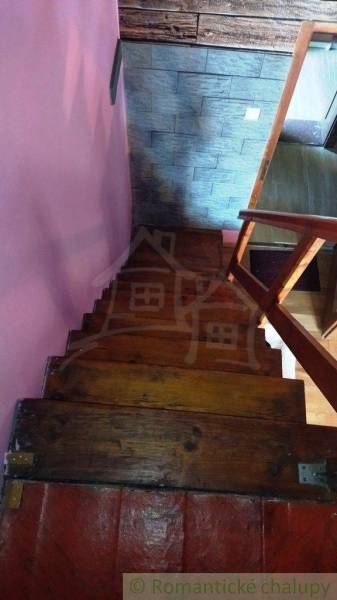Wooden stairs leading down in a cabin with pink walls and textured wall cladding.