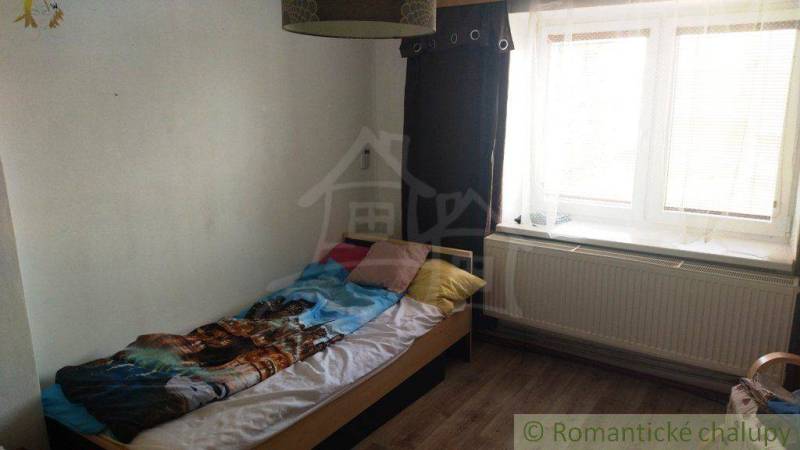 A simple room with a bed, a window, and curtains in a family house.