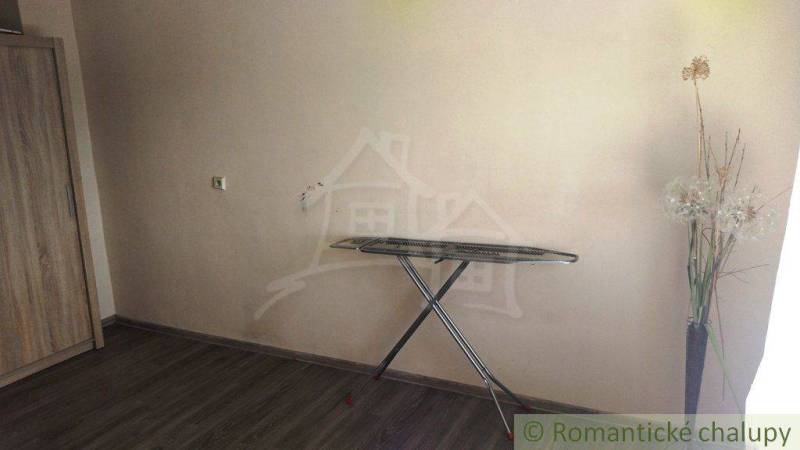 A room in a family house with a wooden wardrobe, an ironing board, and decorative flowers in a vase.