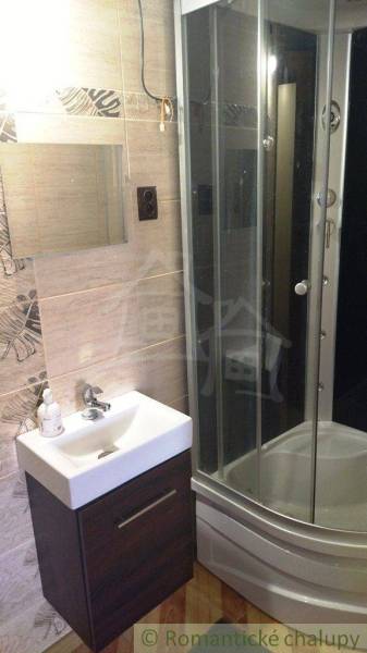 A bathroom in a family house with a sink, a shower, and tiles.