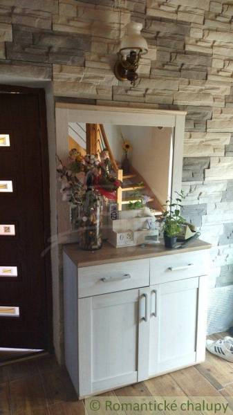 Mirror wall with a sideboard, lamp, and decorations in a family house.
