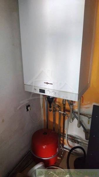 Viessmann boiler in a family house; white unit on an orange wall with piping.