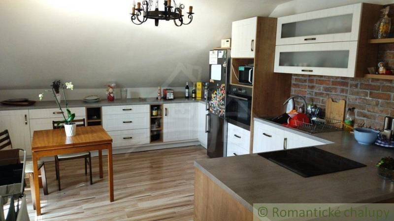 A kitchen in a family house with wooden furniture and brick wall cladding.