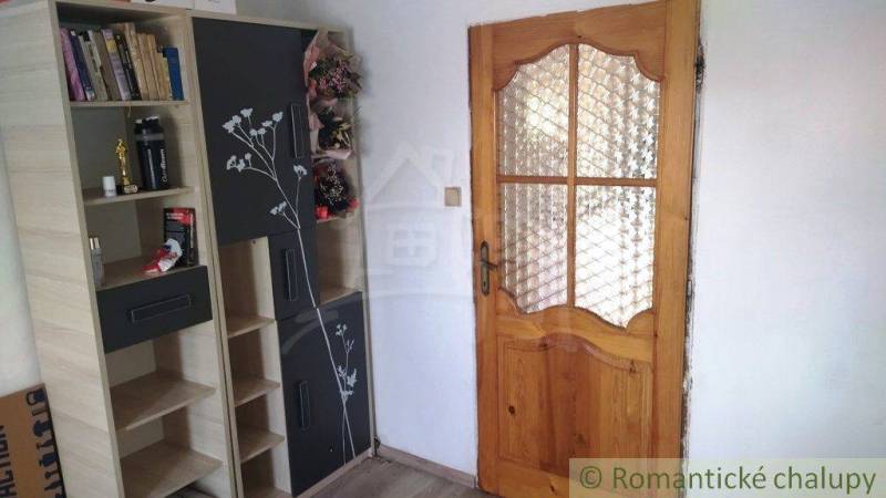 Wooden door in a family house, next to it a shelf with books and decorations.