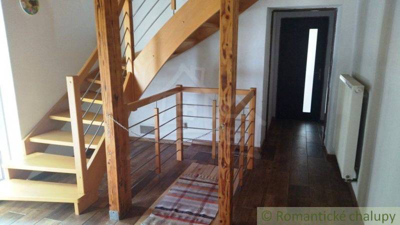 Interior of a family house with a wooden staircase and a dark plank floor.