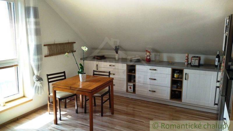 Kitchen area of a family house with a window, table, and white cabinets.