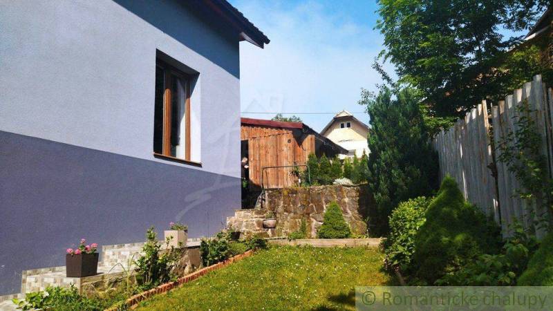 A garden of a family house in Spišská Nová Ves with a wooden cottage and greenery.