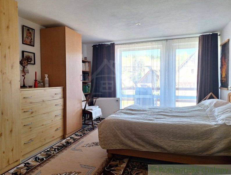 A bright bedroom in a family house with wooden furniture and a view through French windows.