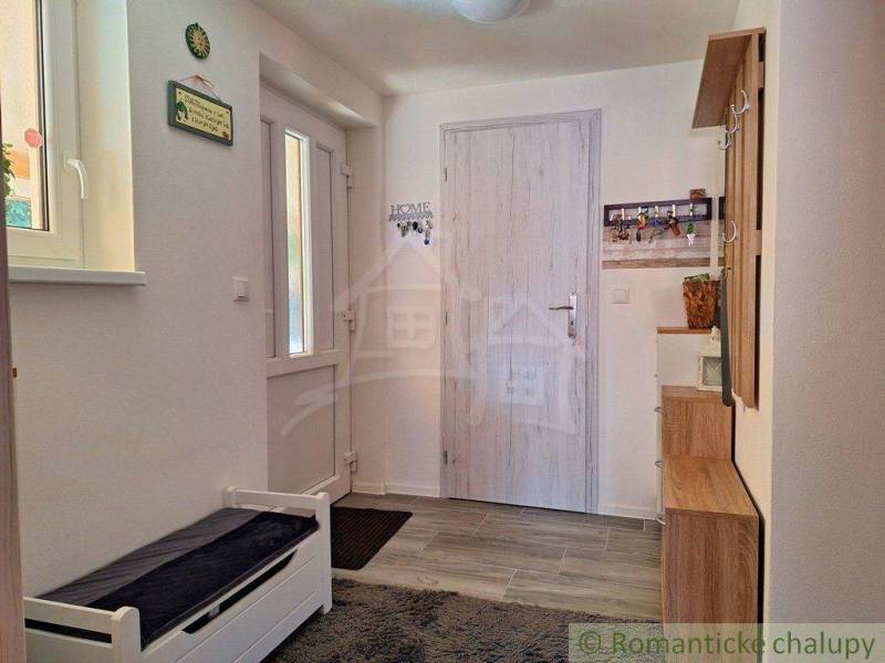 Interior of a family house with an entrance door, a bench, and a coat rack.
