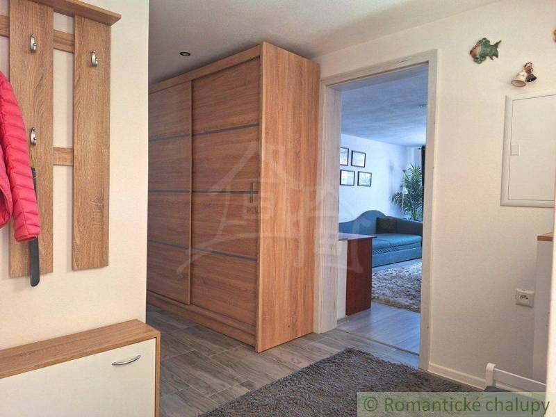 A hallway in a family house with wooden furniture, a coat rack, and a view into the living room.