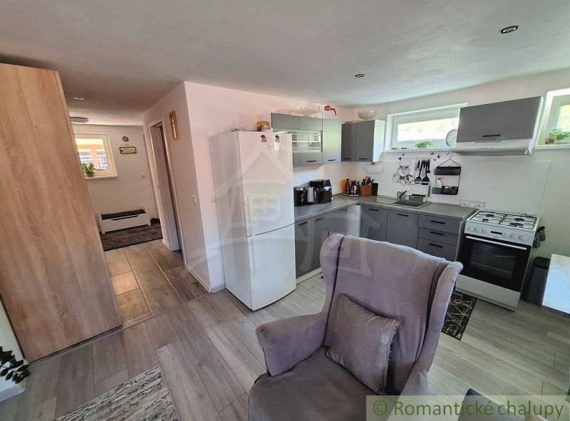 A kitchen in a family house with furniture, appliances, and a chair in a bright space.