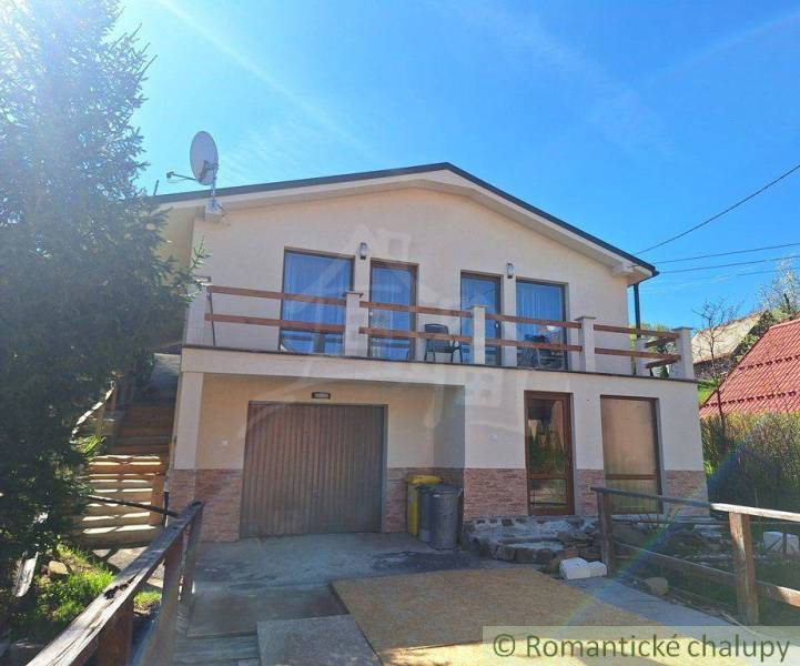 A family house in Liptovský Mikuláš with a balcony and a garage, surrounded by greenery.
