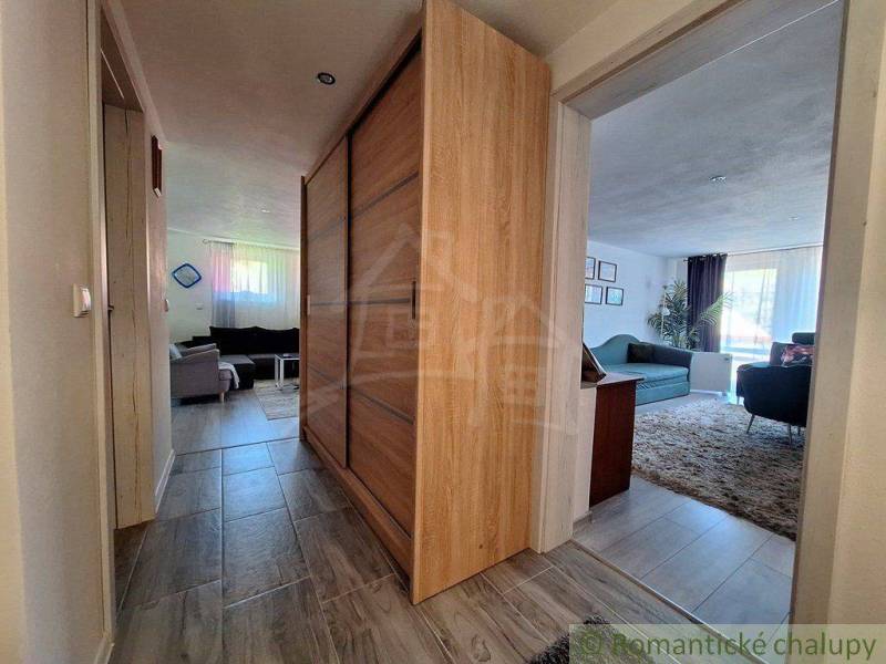 A hallway in a family house with a wooden wardrobe and a living room with a sofa.