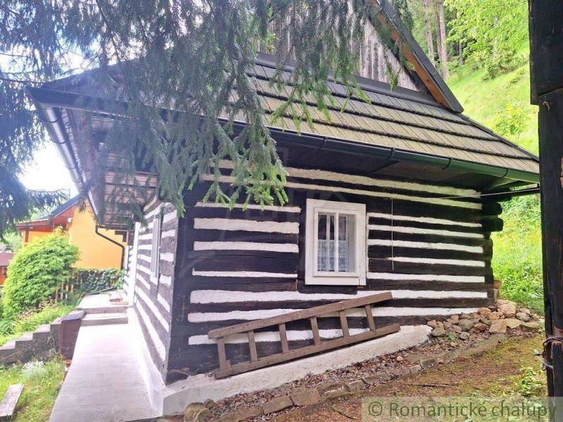 A wooden family house in the forest near Ružomberok, surrounded by greenery and with a shingle roof.