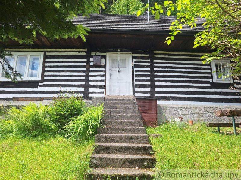 A traditional wooden family house in Ružomberok surrounded by greenery and flowers.