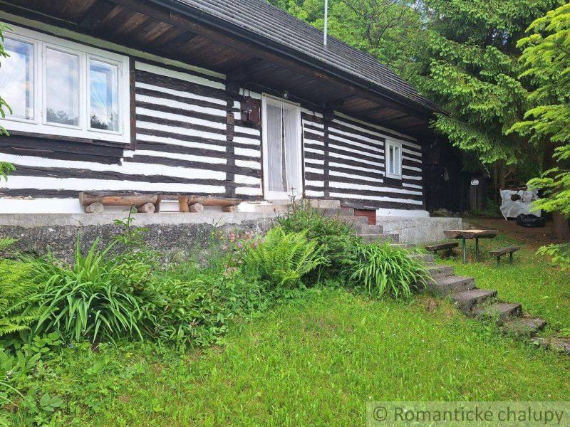 A family house in Ružomberok offers a wooden facade surrounded by greenery and wooden furniture.