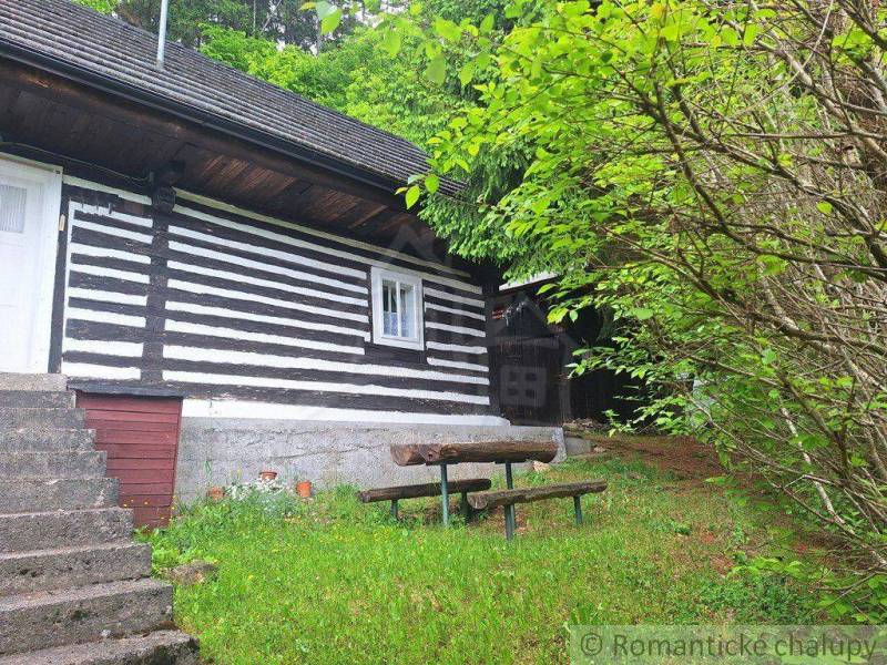 A family house in Ružomberok with a wooden facade and an outdoor seating area surrounded by greenery.