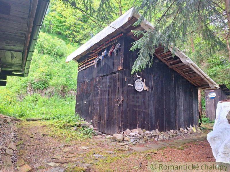A wooden shelter in the garden of a family house in Ružomberok, surrounded by greenery and trees.