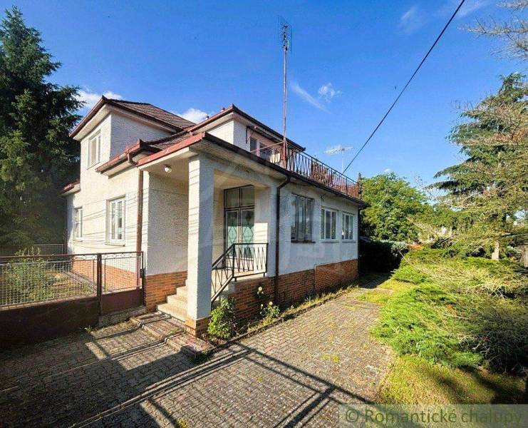 A family house in Plavecký Štvrtok with a white facade and a large garden in summer weather.