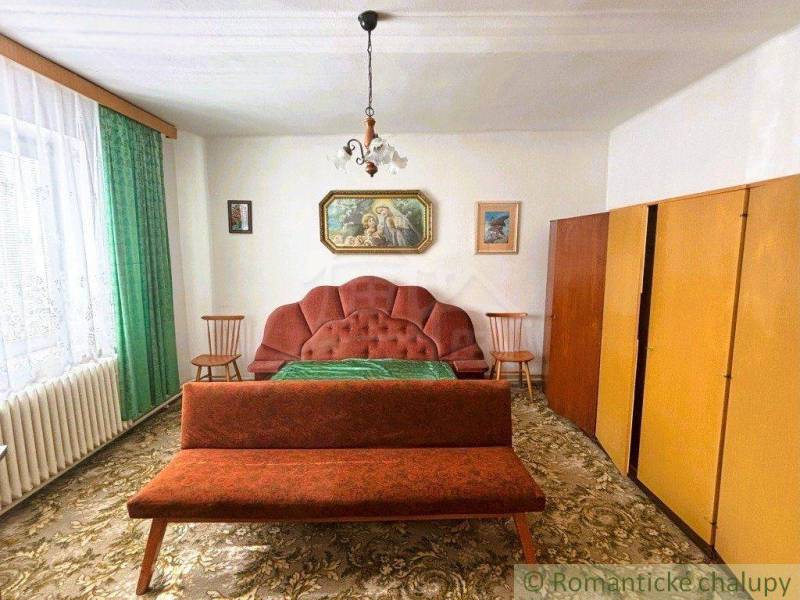 A retro room in a family house with a carpet, furniture, and green curtains.