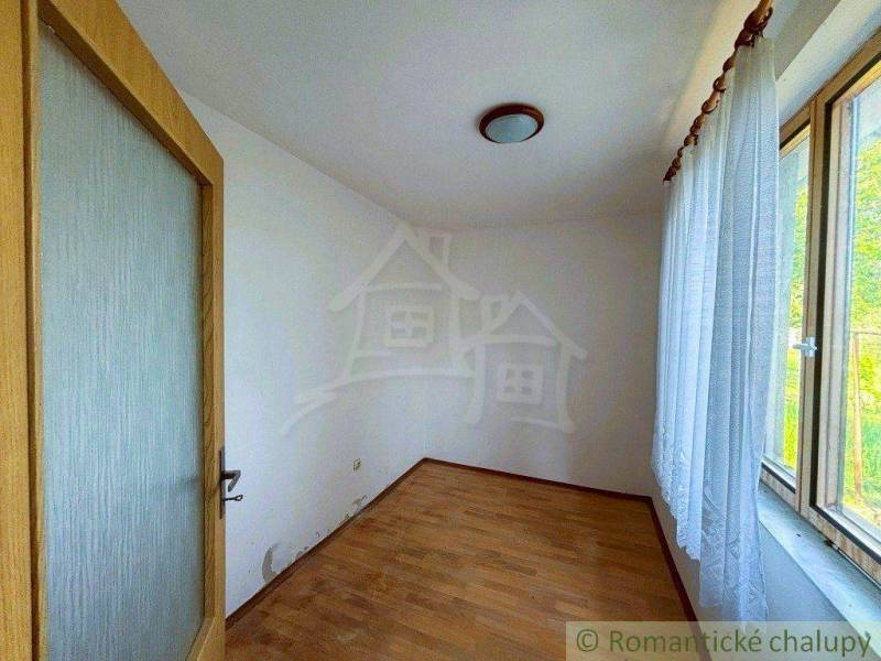 An empty room in a family house with wooden doors and a large window with a curtain.