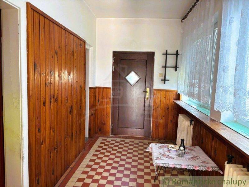 A hallway in a family house with wooden paneling and a tiled floor.