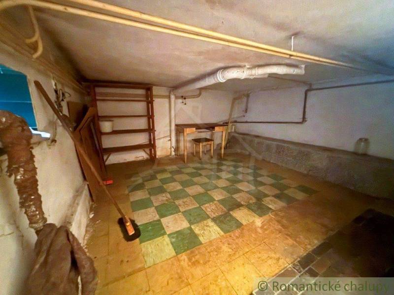 A shop in a family house with a tiled floor, a shelf, and a work table.