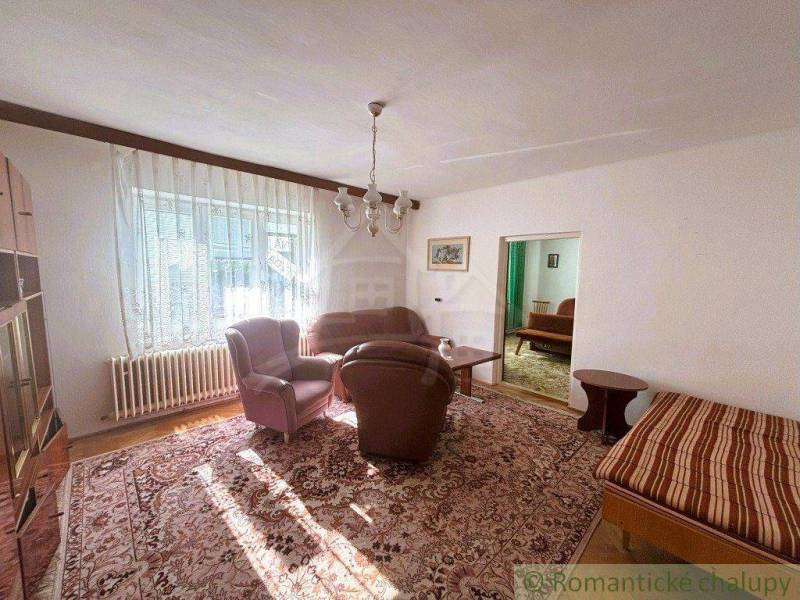Living room of a family house with comfortable armchairs, a sofa, and a large carpet.