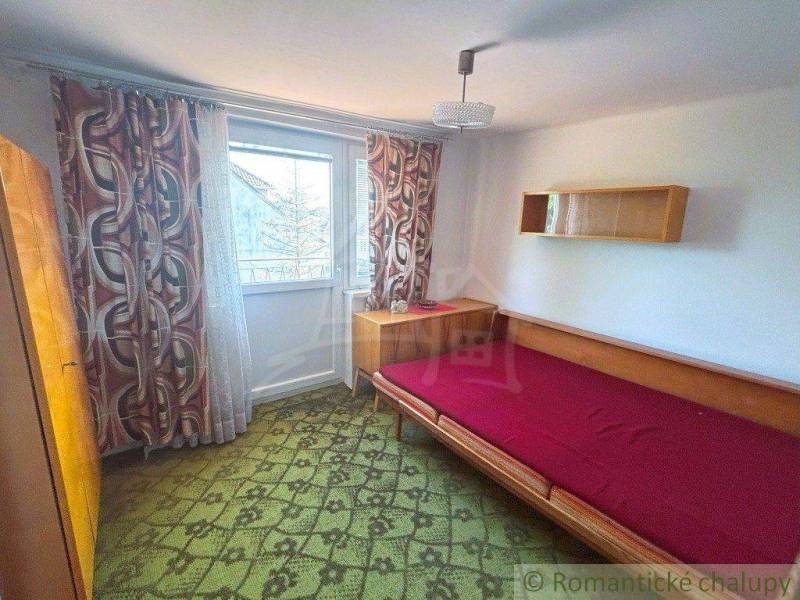A bedroom in a family house with a bed, a cabinet, and decorative curtains.