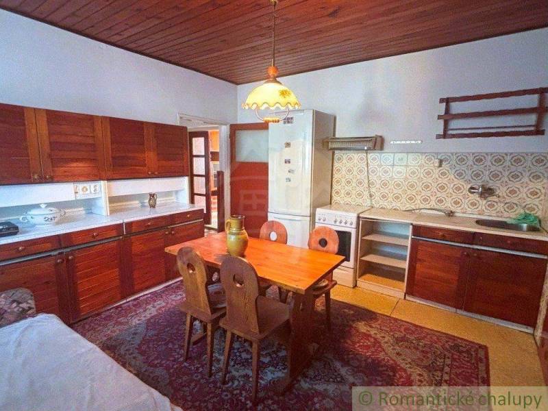 A kitchen in a family house with a wooden ceiling, retro furniture, and patterned tiles.