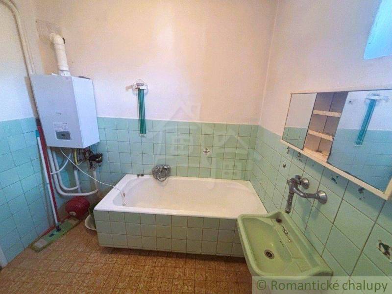 Bathroom in a family house with a bathtub, gas boiler, and mirror with a cabinet.