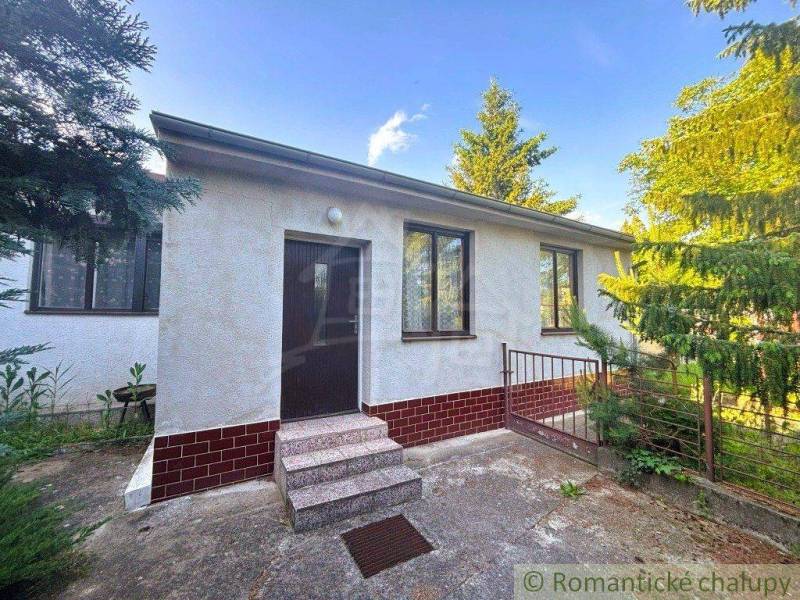A family house in Plavecký Štvrtok with a white facade and a garden surrounded by greenery.